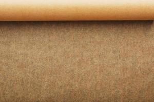 A roll of unfolded brown parchment paper, for baking food in on a dark background, top view. photo