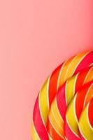 Lollipop multicolored close-up as background texture on pieces on pink background. photo