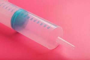 Medical syringe on cyanide, pink background close-up, copy space. The concept of minimalism. photo