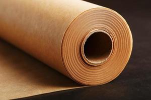 A roll of unfolded brown parchment paper, for baking food in on a dark background, top view. photo