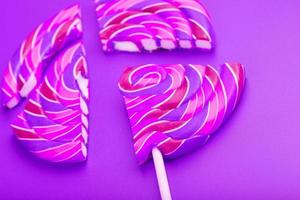 Pink Lollipop split into pieces on a pink background, top view, close-up. photo