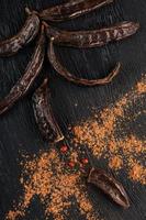 Carob carob fruit with powder on black background. Blast the Sweet powder from the pulp of the pods. photo