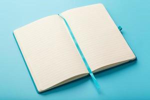 Open notebook, diary with blank and blank pages on a blue background, top view.
