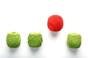 A unique red ball jumps out of a row of identical wool balls. Abstract concept of leadership, photo