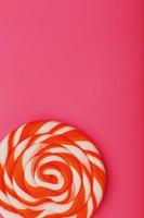 Orange Lollipop on a pink background with a soft contrast. Minimal concept with copy space. photo
