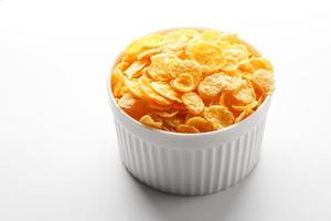 White cup with golden corn flakes isolated on white background. View from above. Delicious and healthy breakfast photo