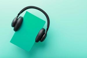 Headphones are worn on a book in a blue hardcover on a blue background, top view. photo