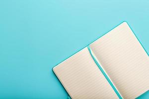 Open notebook, diary with blank and blank pages on a blue background, top view. photo