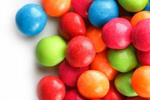 A rainbow of color from multicolored candies close-up, multi-colored glaze dragee on a white background photo