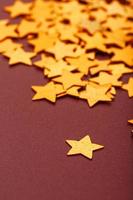 Gold stars on red background. The concept of greeting cards, headlines and web site. A scattering of Golden stars photo