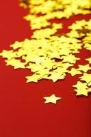 una dispersión de estrellas doradas sobre un fondo rojo. tarjetas de felicitación, titulares y concepto de sitio web. foto