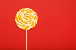 Colorful round Lollipop, on red background. Minimal concept with copy space. photo