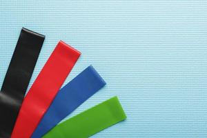 Fitness elastic bands of different colors and loads for sports on a blue background. photo