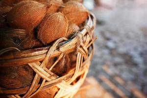 Coconuts in a wicker basket of brown color with fibers lit by sunlight. Stack on the market photo