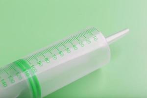 Medical syringe on a green background close-up, copy space. The concept of minimalism. photo