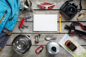 Top view of tourist equipment for travel and tourism on a rustic light wooden floor with an empty space in the middle. photo