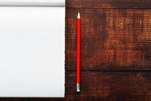 Notepad with red pencil on a brown wooden table background, for education, write goals and deeds photo