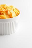 White cup with golden corn flakes isolated on white background. View from above. Delicious and healthy breakfast