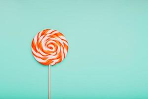 Orange Lollipop on blue background with soft contrast. Minimal concept with copy space. photo