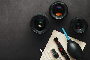 herramientas para limpiar la cámara con lentes sobre un fondo de textura oscura.