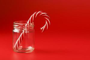 One Lollipop Candy cane in a glass jar on a red background. photo