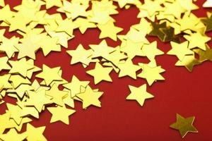 A scattering of Golden stars on red background. The concept of greeting cards, headlines and web site. photo