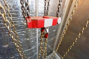 metallic chain handle with red hook in technical room. Crane cargo hook. photo