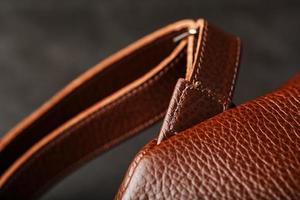 Brown backpack made of textured brown leather on a black stone background. Elegant golden brown women backpack with fashion and rivets photo