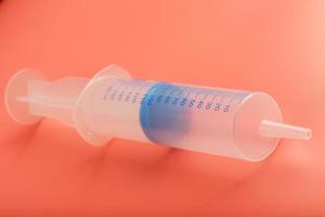 Large medical syringe on pink background with scale, copy space. photo