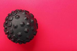 Black lumpy foam body massage ball on red background. photo