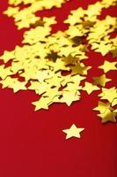 A scattering of Golden stars on red background. The concept of greeting cards, headlines and web site. photo