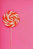 Orange Lollipop on a pink background with a soft contrast. Minimal concept with copy space. photo