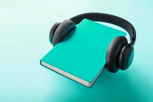 Headphones are worn on a book in a blue hardcover on a blue background, top view. photo