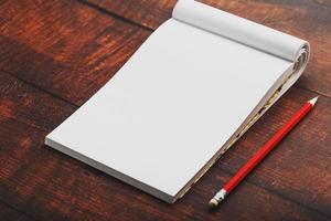 Notebook with a red pencil on a brown background with warm sunlight, for writing. Free empty space for writing on a blank sheet of a notebook. photo