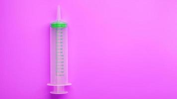 Green medical syringe on crazy lilac background. The concept of minimalism and free space. photo