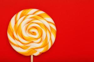 Colorful round Lollipop, on red background. Minimal concept with copy space. photo