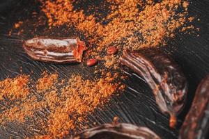 Carob fruit on a black textured background in the shape of an exploding flower. photo