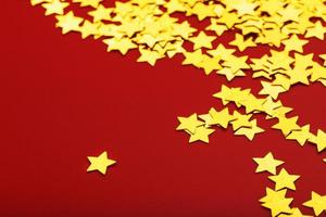 estrellas doradas sobre fondo rojo. el concepto de tarjetas de felicitación, titulares y sitio web. una dispersión de estrellas doradas foto