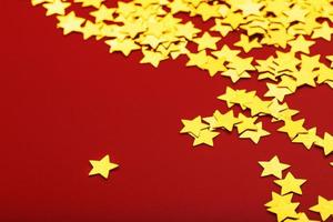 Gold stars on red background. The concept of greeting cards, headlines and web site. A scattering of Golden stars photo