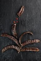 The fruit of the carob tree on black textured background in the form photo