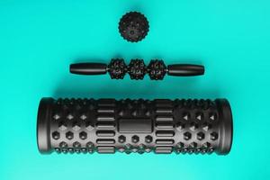 A set of black bumpy foam massage rollers, body rollers, rubber balls on a blue background. photo