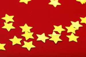 A scattering of Golden stars on red background. The concept of greeting cards, headlines and web site. photo