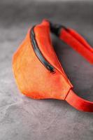 Waist bag made of red leather, banana on a gray background. Handmade photo