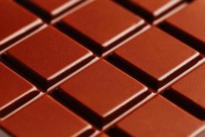 textura de chocolate negro de cerca. segmentos de una barra de chocolate en macro. textura de fotograma completo foto