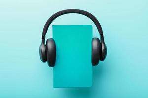 Headphones are worn on a book in a blue hardcover on a blue background, top view. photo