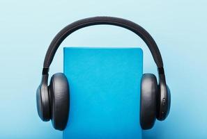 Headphones are worn on a book in a blue hardcover on a blue background, top view. photo