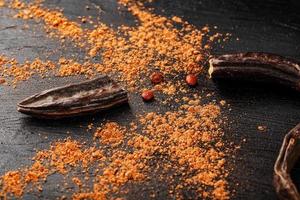 Carob carob fruit with powder on black background. Blast the Sweet powder from the pulp of the pods. photo