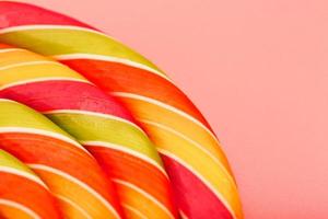 Lollipop multicolored close-up as background texture on pieces on pink background. photo