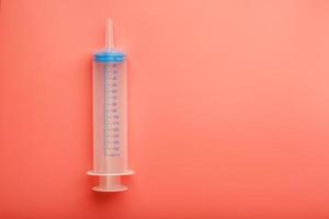 Large medical syringe on pink background with scale, copy space. photo