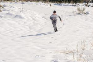child running in the snow on a sunny day photo